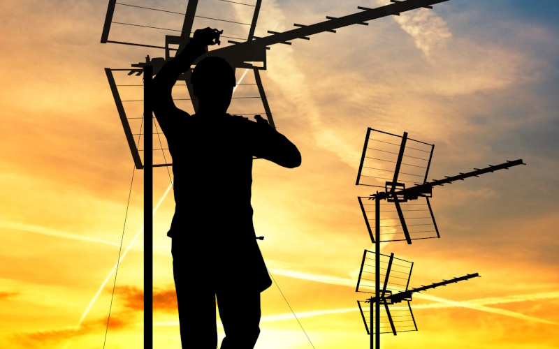 TV Repair man fixing antenna on a roof